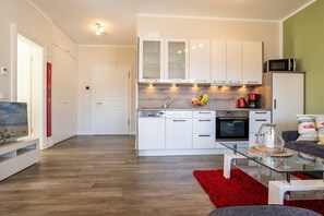 A modern kitchen with white cabinets, a dishwasher, an oven, and a microwave. - No. 20 in Villa Poseidon (Ostseebad Binz)