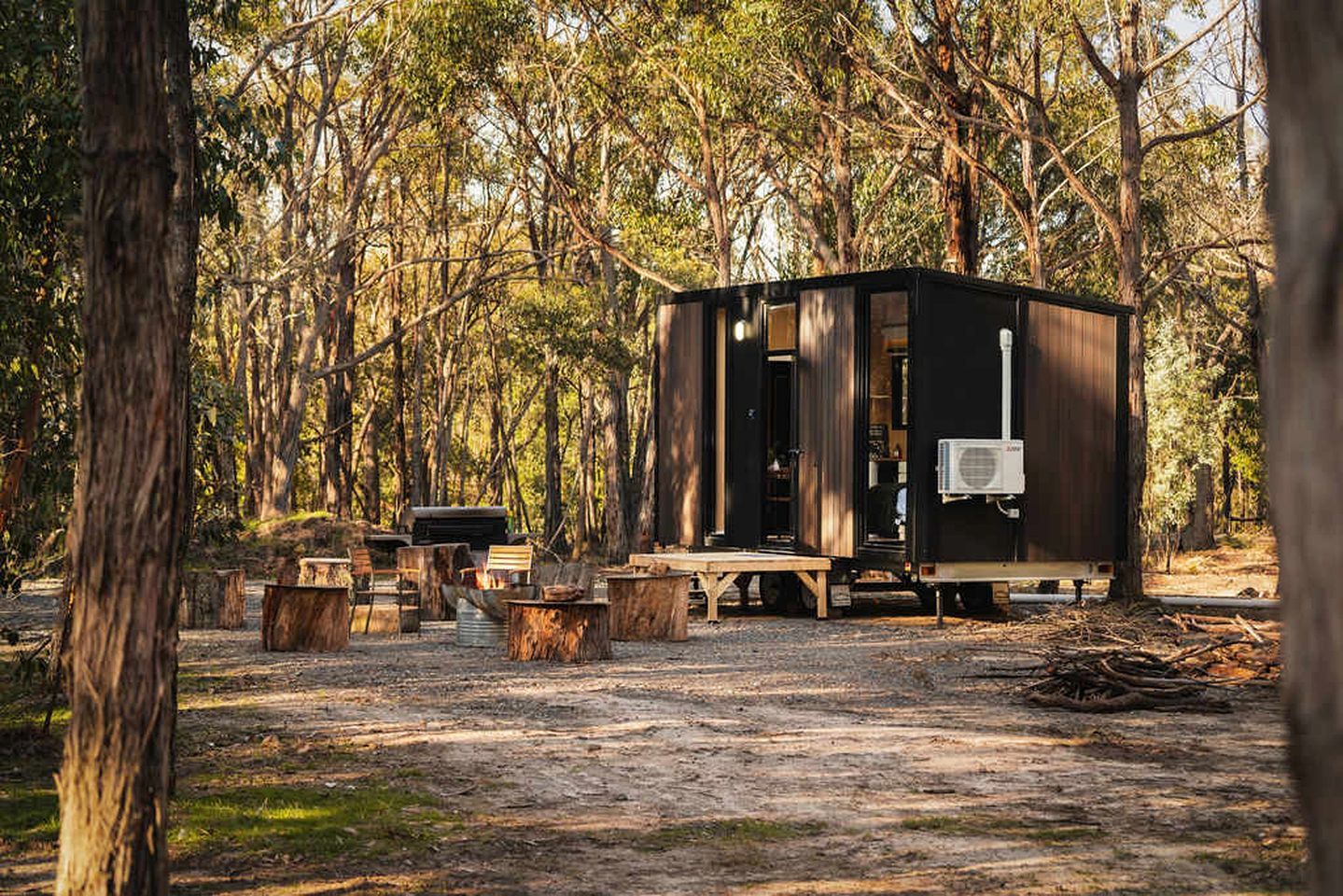 A rustic cabin with a small deck, surrounded by trees.