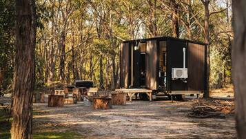 A rustic cabin with a small deck, surrounded by trees.