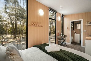 Un dormitorio moderno con una cama grande, una pared de madera y vistas al exterior.