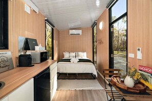 A compact room with a bed, a desk, and a window.