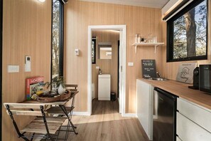 A modern kitchen with a wooden countertop, a dining area with a table and chairs, and a view of the outdoors through a window.