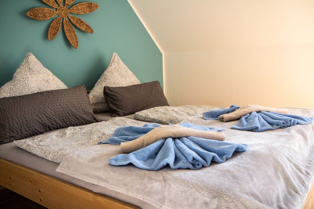 Ein Bett mit gemusterten Betttextilien, Kissen und einem dekorativen Wandbild.