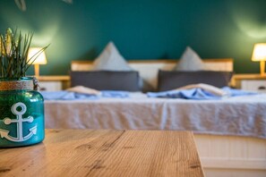 A bedroom with a bed, pillows, a nightstand, a lamp, and a plant in a jar.
