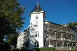 Ein mehrstöckiges Gebäude mit einem markanten Turm, Balkonen und blauem Himmel.