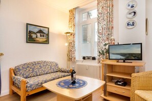 A cozy living room with a sofa, a small table, a television, and a radiator. - Marie-Luise at Villa Stranddistel (Ostseebad Binz)