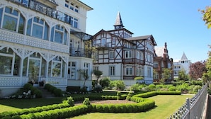 A traditional European-style building with a well-maintained garden and a clear sky. - "Wave Play" at Villa Freia (Binz)
