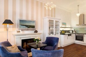 Un salon avec une cheminée, un téléviseur et un coin repas avec des chaises.