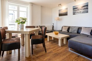 A modern living room with a wooden dining table, leather chairs, a sofa, and a coffee table. - No. 5 (Summer Wind) in Villa Helene (Ostseebad Binz)