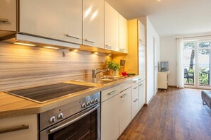 A modern kitchen with a built-in oven, stainless steel appliances, and a wooden countertop. - No. 5 (Summer Wind) in Villa Helene (Ostseebad Binz)