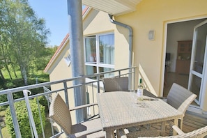 Ein Balkon mit Korbmöbeln, einem Tisch und einer Weinflasche.