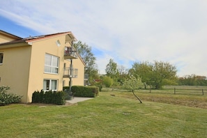Ein zweigeschossiges Wohnhaus mit Balkon, einem gepflegten Rasen und einem Zaun im Hintergrund.