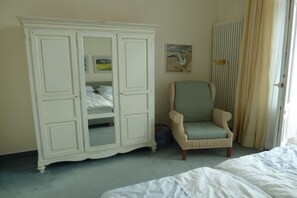 Ein Schlafzimmer mit einem Bett, einem Kleiderschrank, einem Sessel und einem Bild an der Wand.