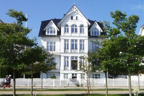 A large, white, multi-story building with a symmetrical facade, a central entrance, and a white picket fence in front. - (No. 8) in Villa Fortuna (Bansin)