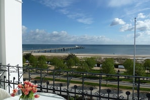 Ein Balkon mit Blick auf einen Strand, einen Steg und einen klaren Himmel.