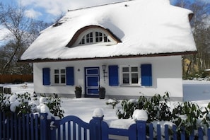 Ein weißes Gebäude mit blauen Fensterläden und einem mit Schnee bedeckten Dach.