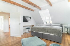 A bedroom with a sloped ceiling, a bed, a TV, and a window. - Lokelk Hüs (Happy House) (Süderende \/ Föhr)
