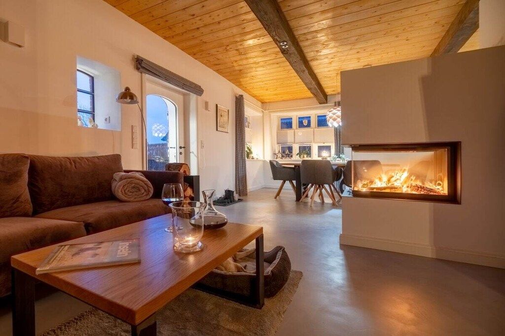 Un salón acogedor con chimenea, un sofá, una mesita de centro y una zona de comedor al fondo.
