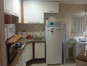 Eine kleine Küche mit Mikrowelle, Kühlschrank, Spüle und Geschirrständer.