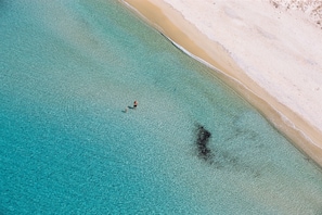 An aerial view of a beach with clear turquoise water and a sandy shore. - Naxian Rhapsody Luxury Villas & Suites (Naxos)