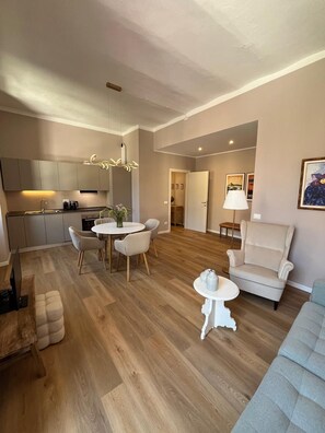 A modern living room with a dining area, a sofa, a chair, and a small table. - San Rocco Apartment in Verbania (Verbania)