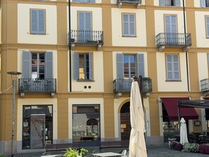 A multi-story building with balconies, a storefront, and outdoor seating. - San Rocco Apartment in Verbania (Verbania)