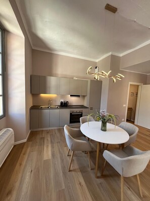 Una cocina moderna con electrodomésticos integrados, un comedor con mesa y sillas redondas, y una lámpara colgante.