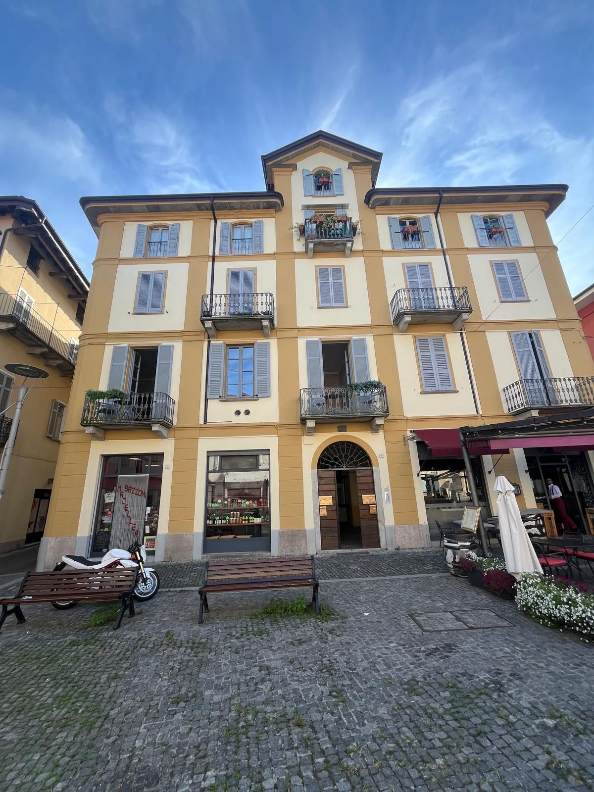 A multi-story building with a ground-level shop and a café with outdoor seating.