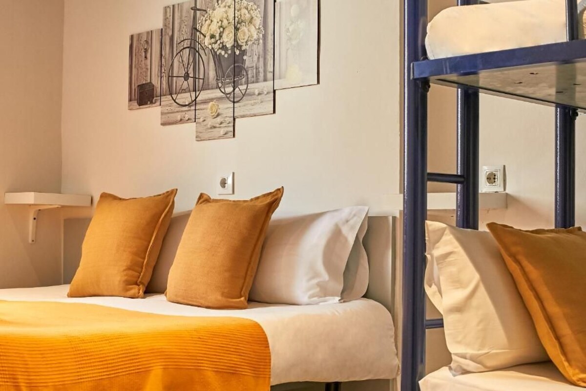Ein Hotelzimmer mit einem Bett, einem Etagenbett und einer Wand mit Kunstwerken.