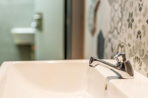 Ein Badezimmerwaschbecken mit Chromarmatur und fließendem Wasser.