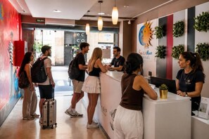 Un espace d’accueil avec un comptoir, un panneau indiquant « SORTIE », et un mur orné d’un motif représentant le soleil et la lune.