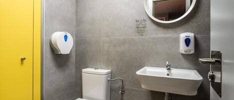 Un baño con inodoro, lavamanos y espejo.