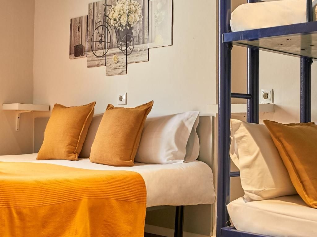 A hotel room with a bed, a bunk bed, and a wall with artwork.