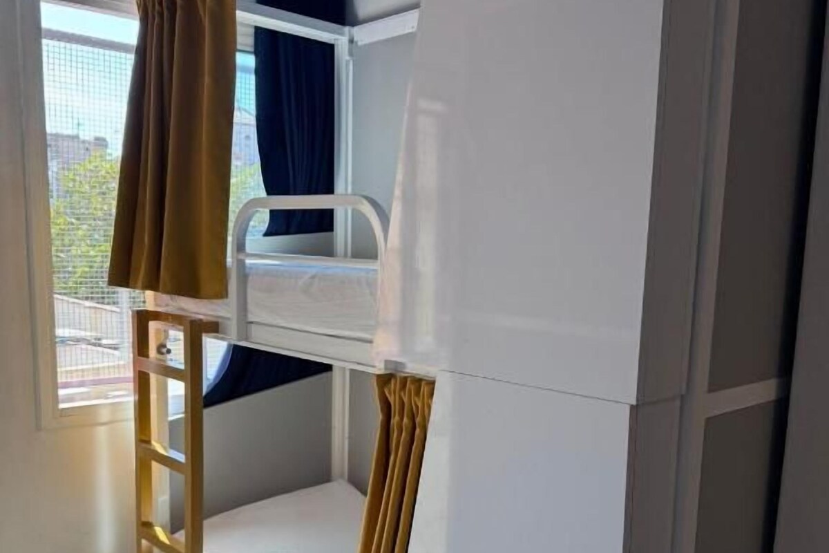 Ein Schlafraum mit Etagenbetten, einem Fenster, Vorhängen und einer Himmelsleiter.