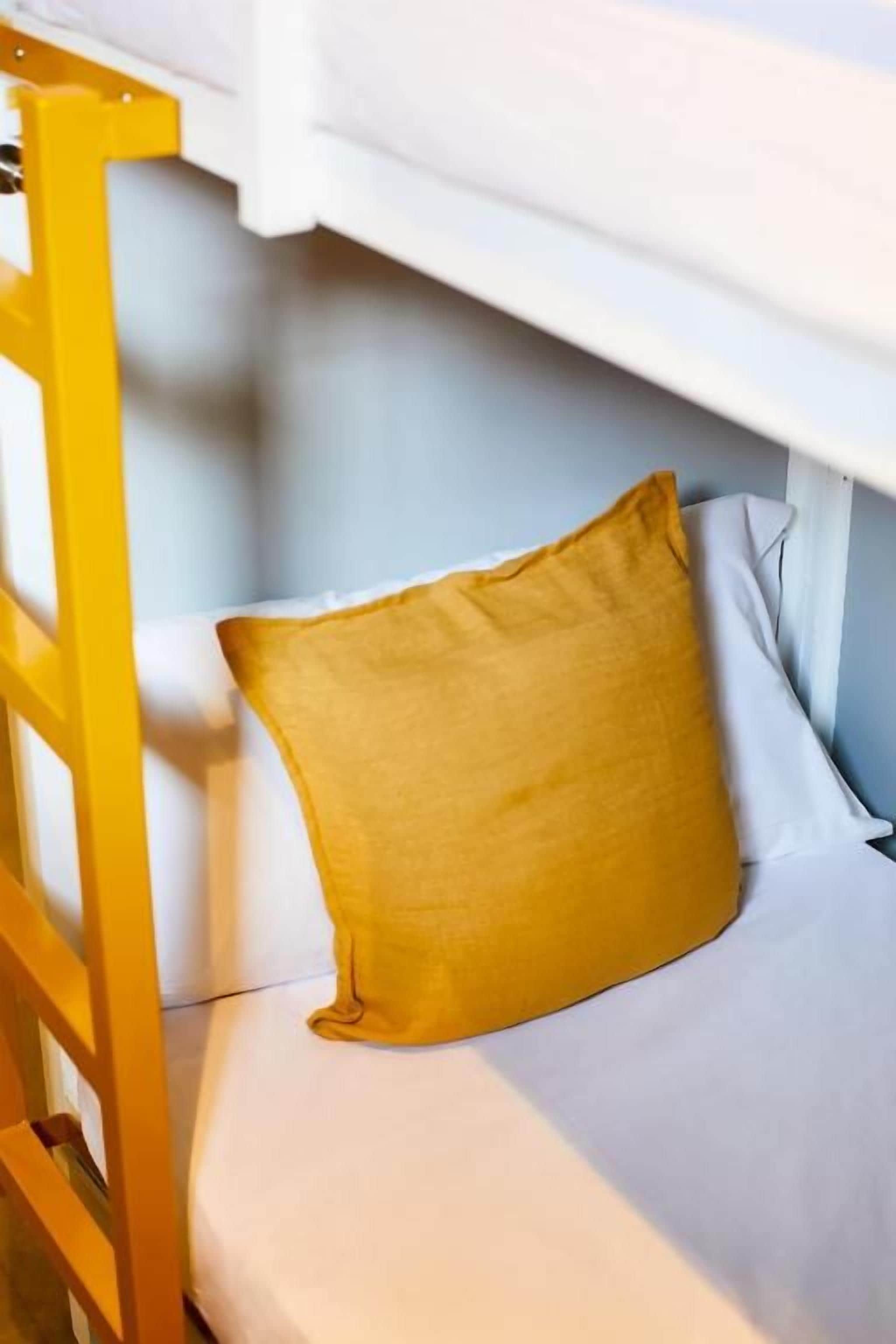 Un lit superposé avec un oreiller jaune et un matelas blanc.