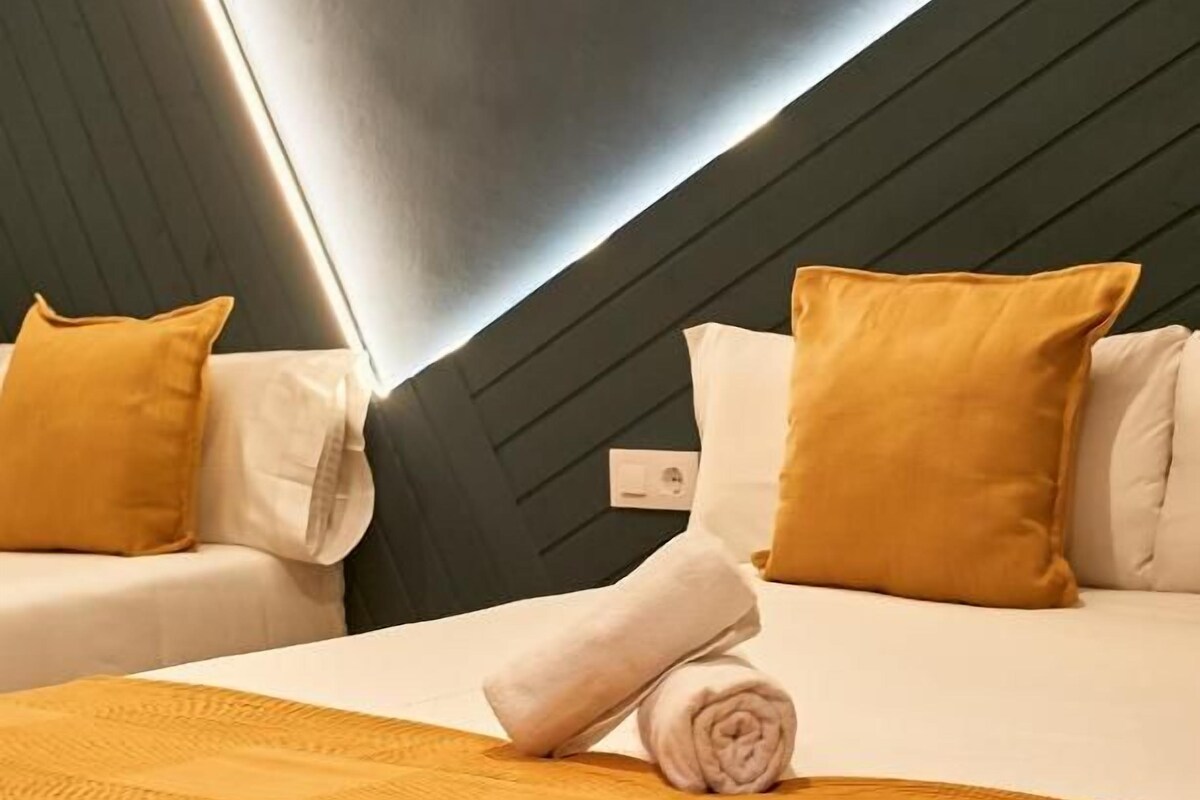 Ein Hotelzimmer mit zwei Betten, einer dunklen Decke und einer Wandleuchte.