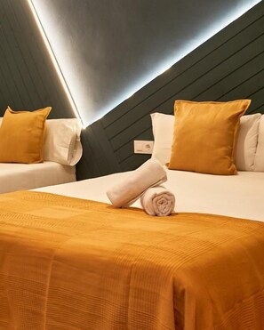 Ein Hotelzimmer mit zwei Betten, einer dunklen Decke und einer Wandleuchte.