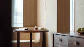A corner of a room with a wooden chair, a small round table, and a glass of amber liquid.
