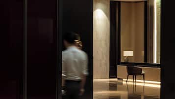A modern interior with a reflective floor, a glass partition, and a seating area with a lamp.