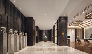 A modern hotel lobby with a marble floor, dark wood paneling, and a row of stone lion statues. - Guilin Exhibition International Hotel (Guilin)