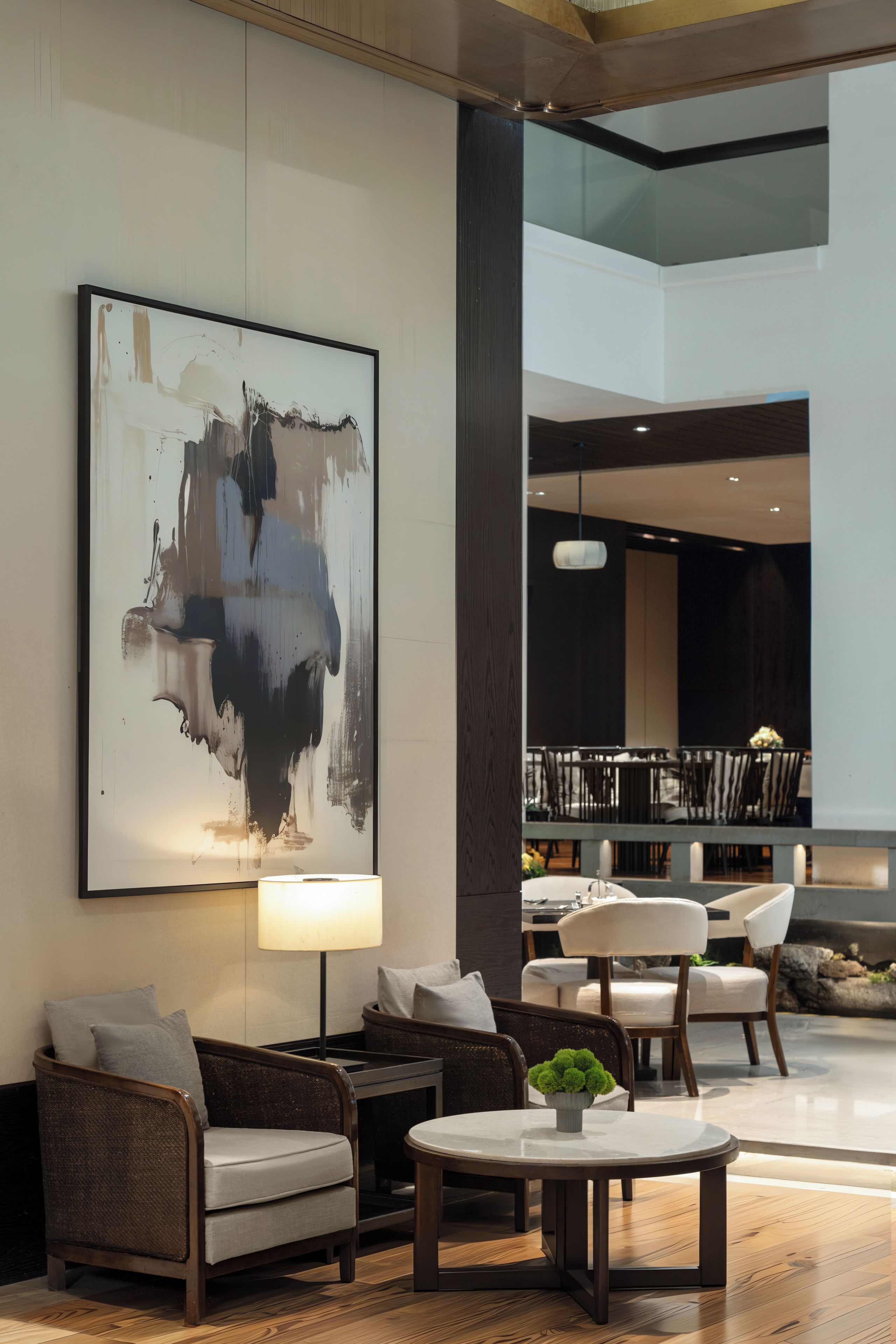 Un'accogliente hall moderna con un grande quadro astratto, un'area salotto con tavolo e sedie, e vista sulla sala da pranzo.
