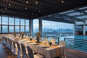 A long dining table set for a formal meal with a city view through large windows. - Guilin Exhibition International Hotel (Guilin)