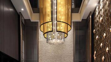 A modern lobby with a large chandelier, seating area, and decorative wall panels.