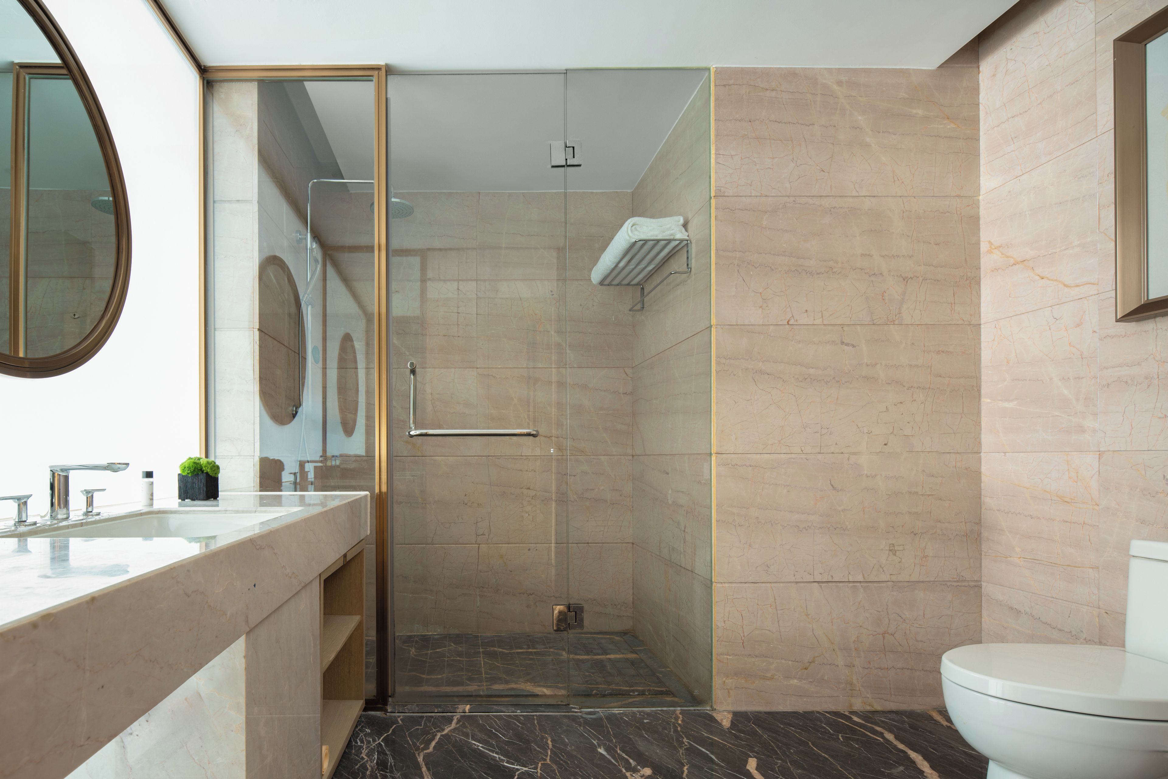 Un baño moderno con cabina de ducha de vidrio, un inodoro y un lavamanos con espejo.