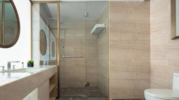 Un baño moderno con cabina de ducha de vidrio, un inodoro y un lavamanos con espejo.