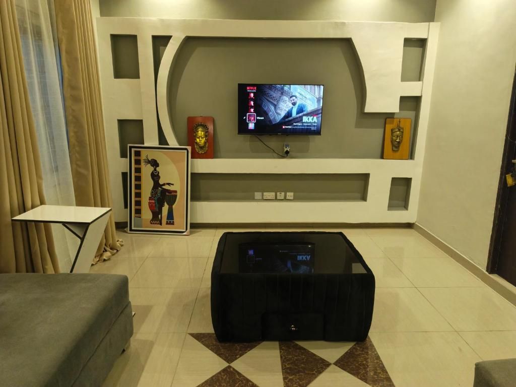 Una sala de estar con un televisor de pantalla plana montado en la pared, una mesa de centro y un cuadro enmarcado en la pared.