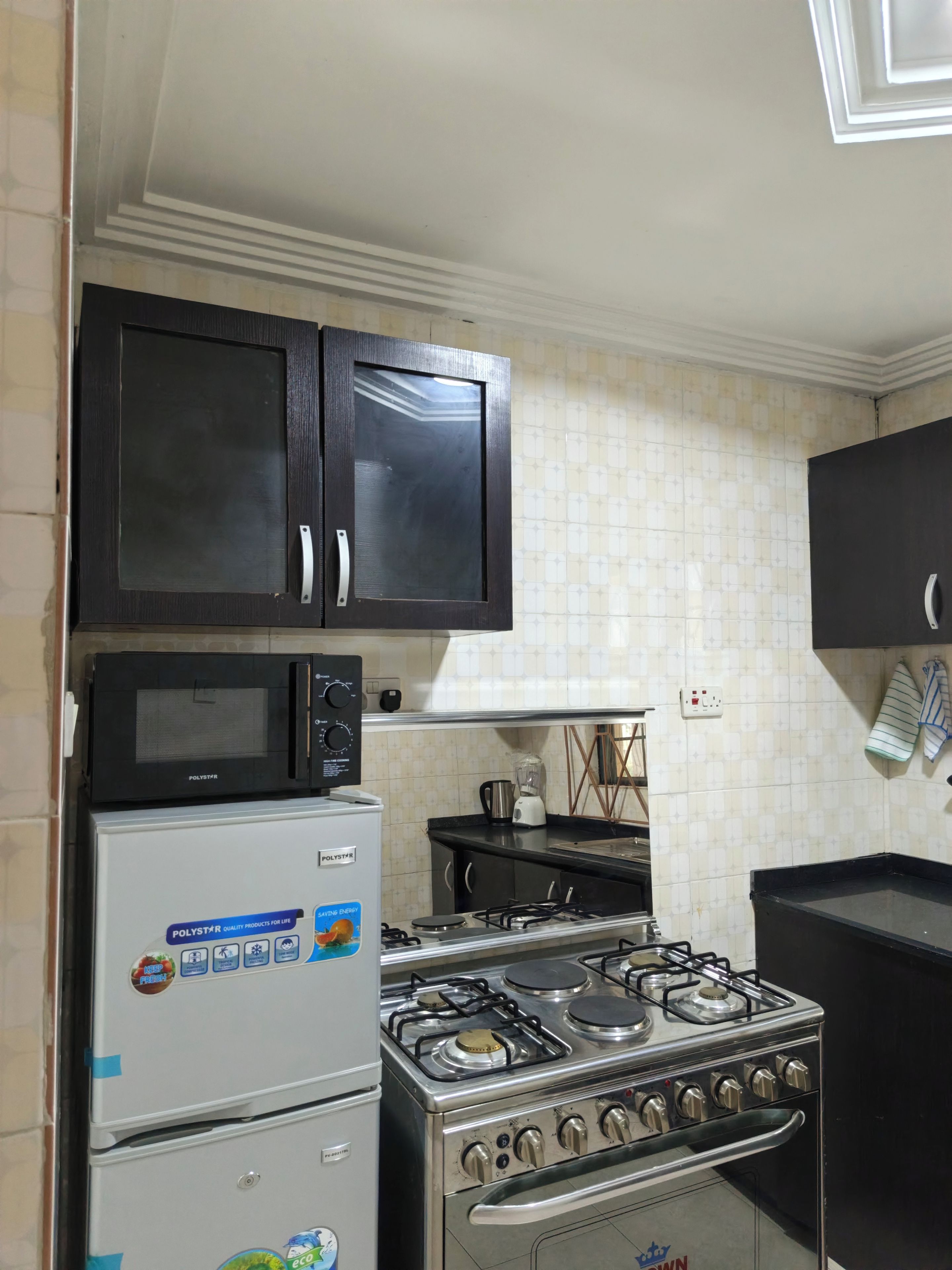 Une cuisine équipée d’un réfrigérateur, d’un four à micro-ondes, d’une cuisinière et de placards.