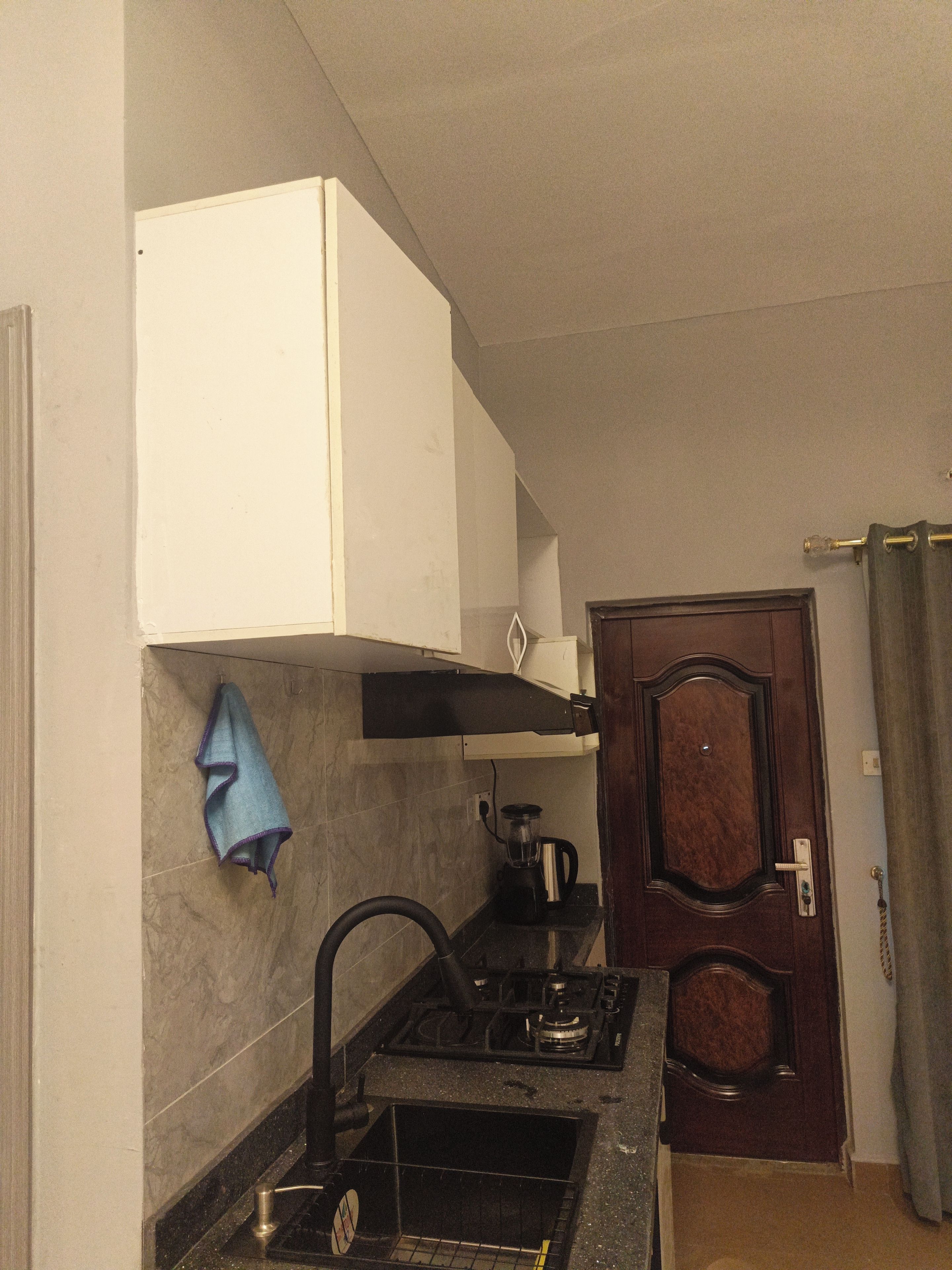 Una cocina con estufa, lavamanos y un armario.
