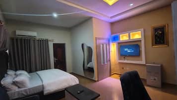 Een hotelkamer met een bed, nachtkastje, televisie en een spiegel.