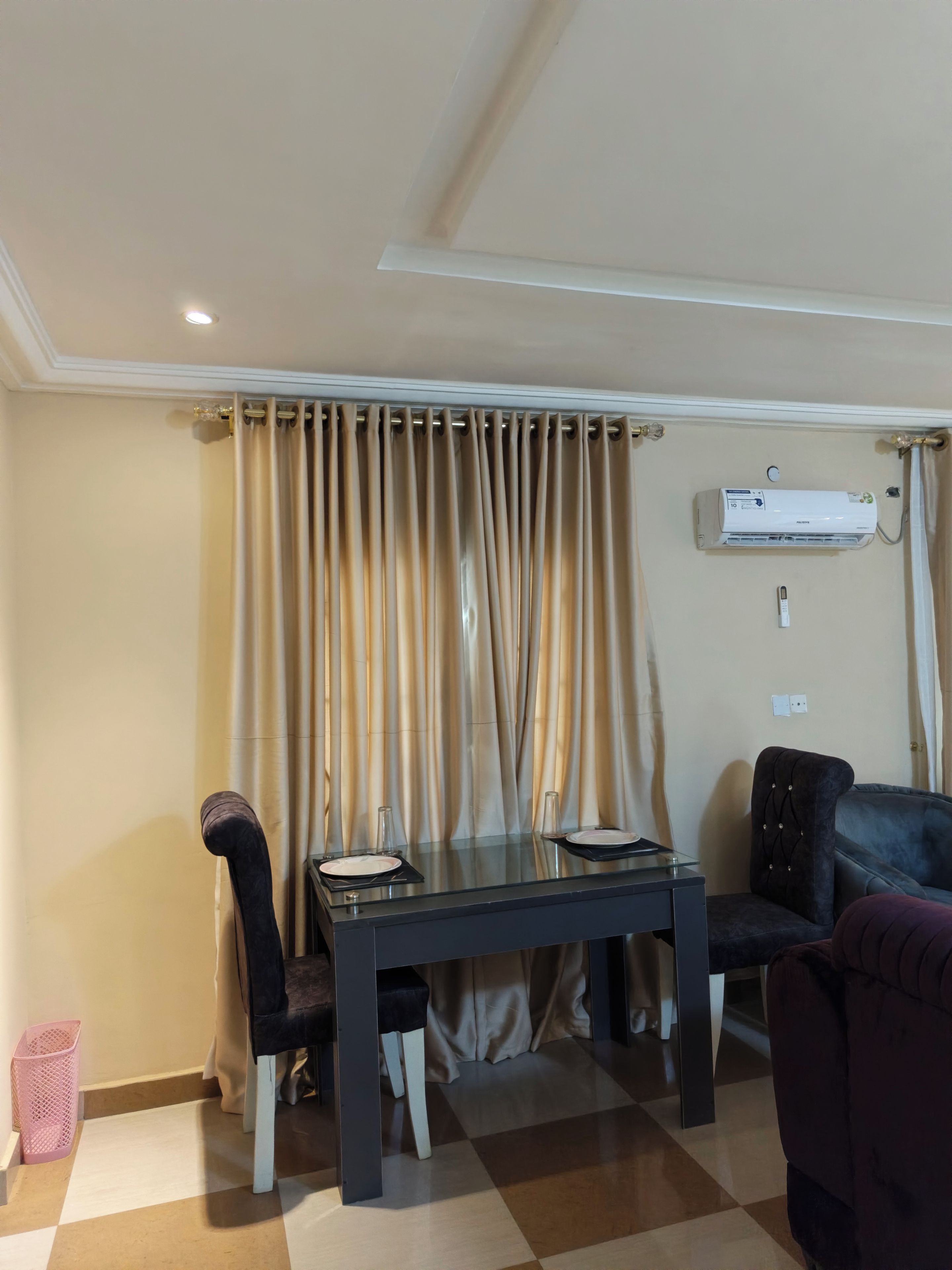 A dining area with a table, chairs, and an air conditioning unit mounted on the wall.